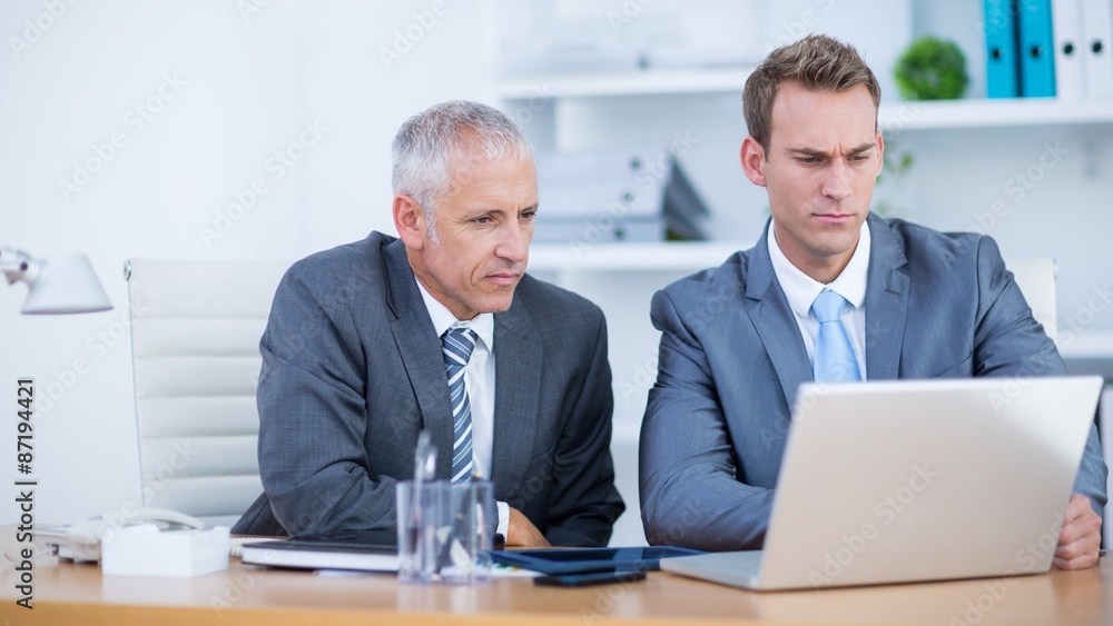 Serious businessmen working together on laptop Serious businessmen working together on laptop