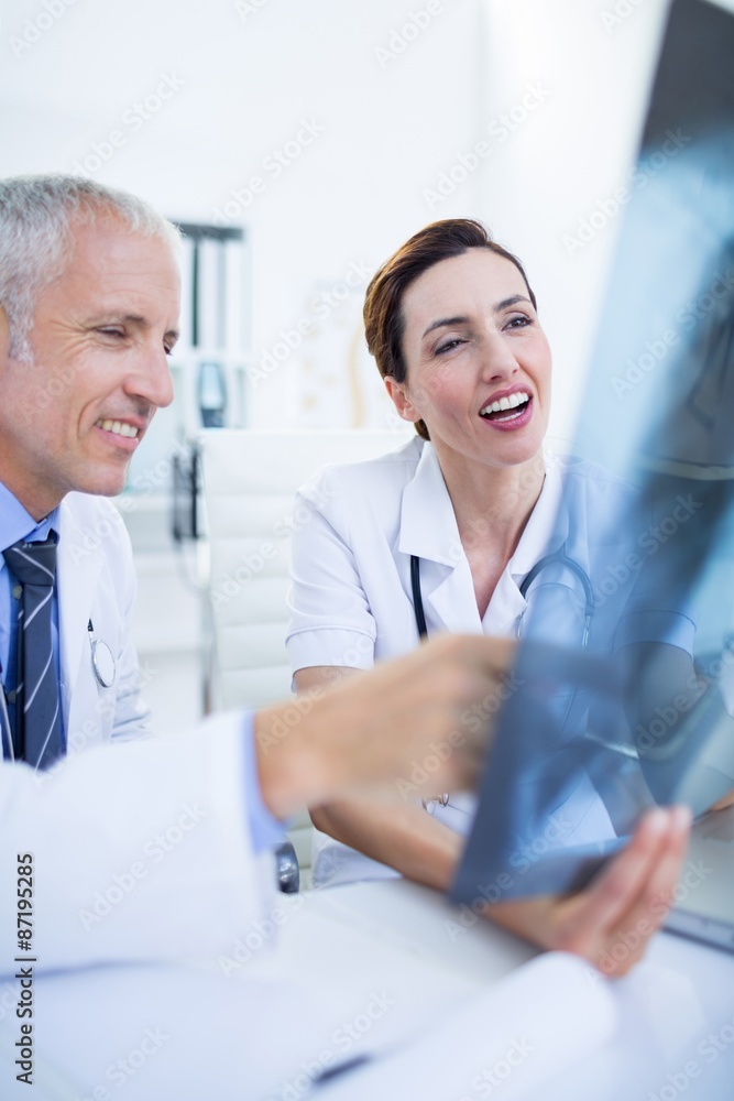 Smiling medical colleagues examining x-ray together