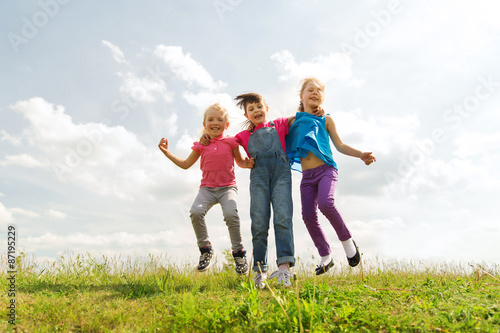 group of happy kids jumping high on green field