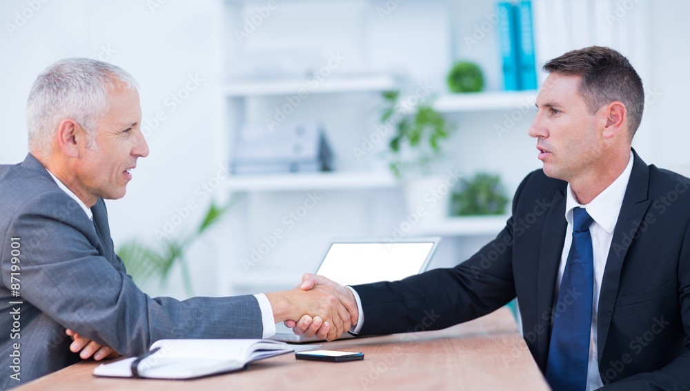Two businessmen shaking hands and working Two businessmen shaking hands and working