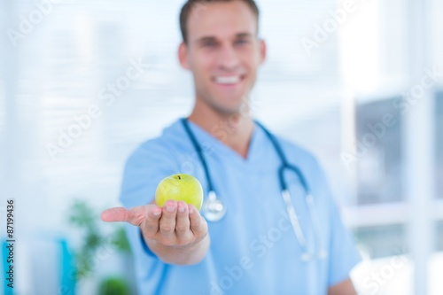 Smiling doctor presenting a green apple