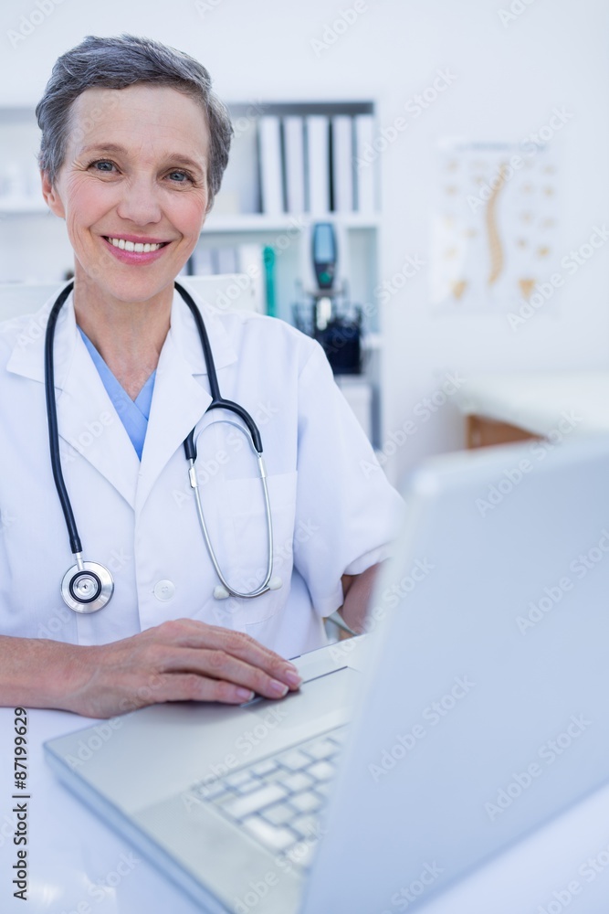 Happy doctor looking at camera and using her smartphone Happy doctor looking at camera and using her smartphone
