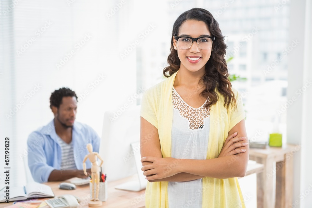 Smiling woman posing in front of her colleague with arms crossed
