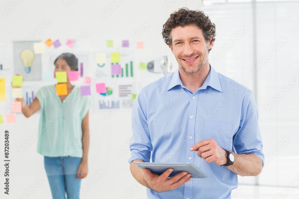 Happy businessman looking at camera with colleague behind Happy businessman looking at camera with colleague behind