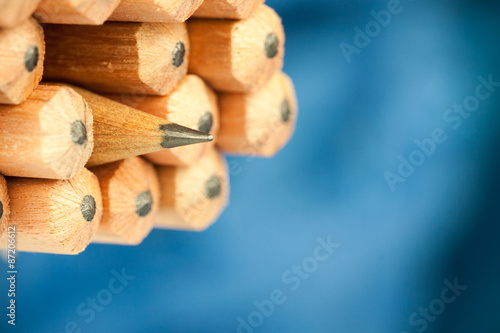 Macro image of graphite tip of a sharp ordinary wooden pencil as drawing and drafting tool, standing among other pencils, symbolizing individuality approach and concept as standing out from the crowd