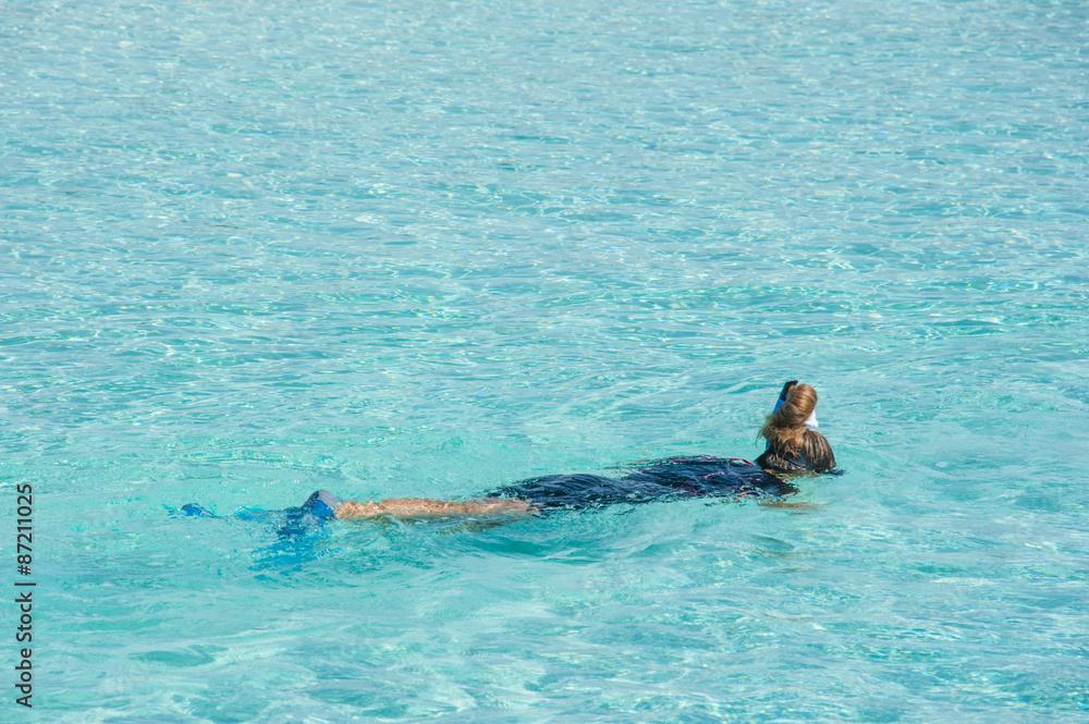Woman snorkeling in crystal clear turquoise water at tropical beach, Maldives Island.