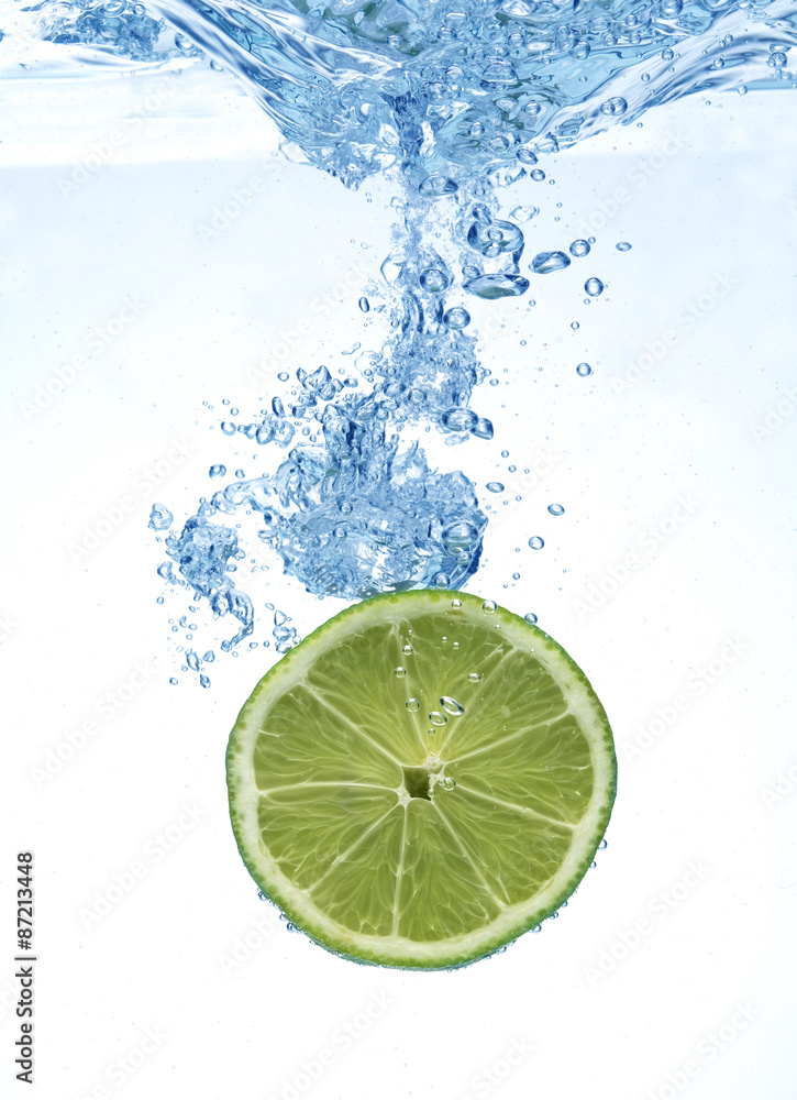 slice of lime droped in the water above white background slice of lime droped in the water above white background