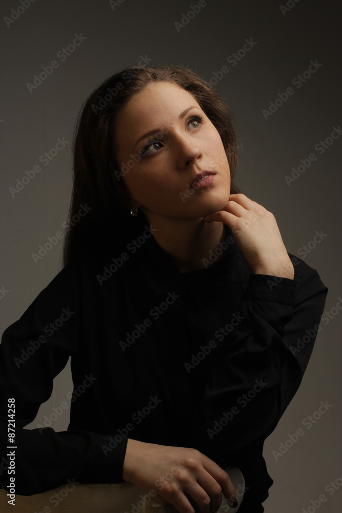 portrait of the beautiful young girl with dark hair in the black blouse looking mysteriously up portrait of the beautiful young girl with dark hair in the black blouse looking mysteriously up