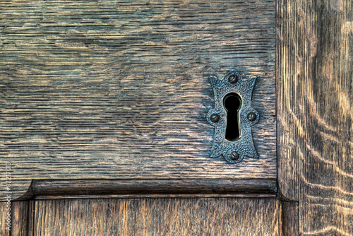 Keyhole with metal plate in a wooden door