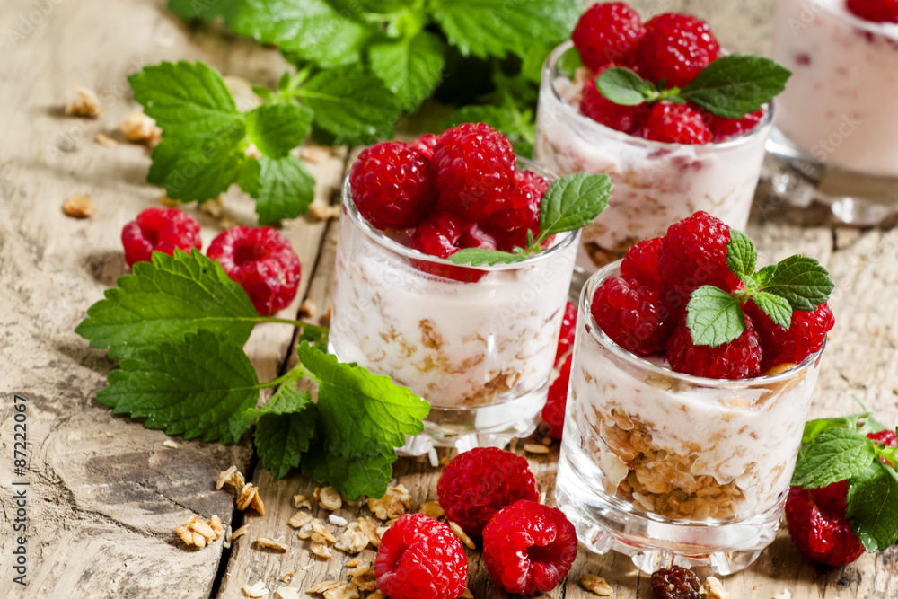Homemade granola with yogurt, raspberry and mint in glass bowls Homemade granola with yogurt, raspberry and mint in glass bowls
