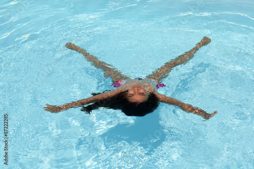 Young woman floating in a pool in star formation