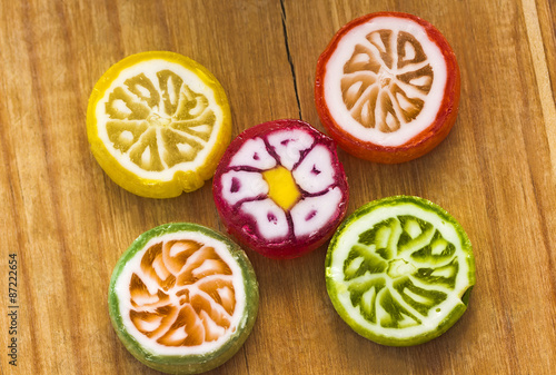 Five round colorful lollipops on wooden table top view.