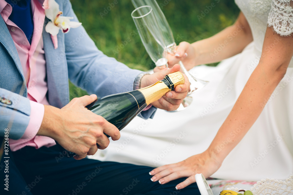 groom opens a bottle of champagne groom opens a bottle of champagne