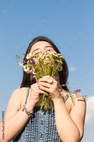 Cute brunette girl admires a bouquet of wildflowers
