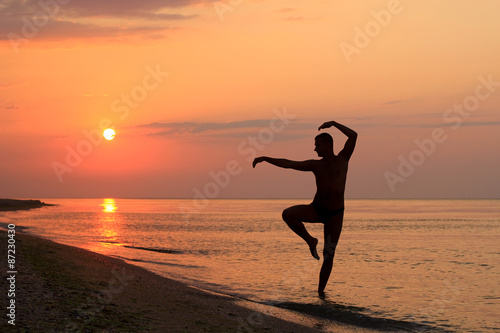 man silhouette doing wushu poses on the beach at sunrise