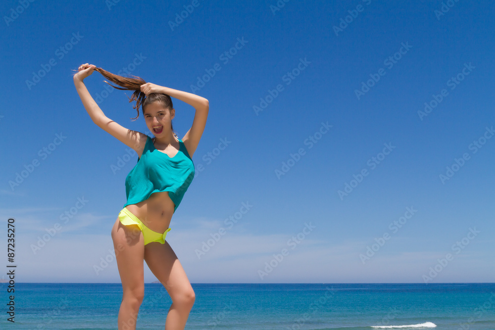 Brunette teen in bikini and beachwear enjoys the summer sun.