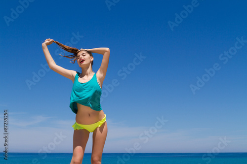 Brunette teen in bikini and beachwear enjoys the summer sun.