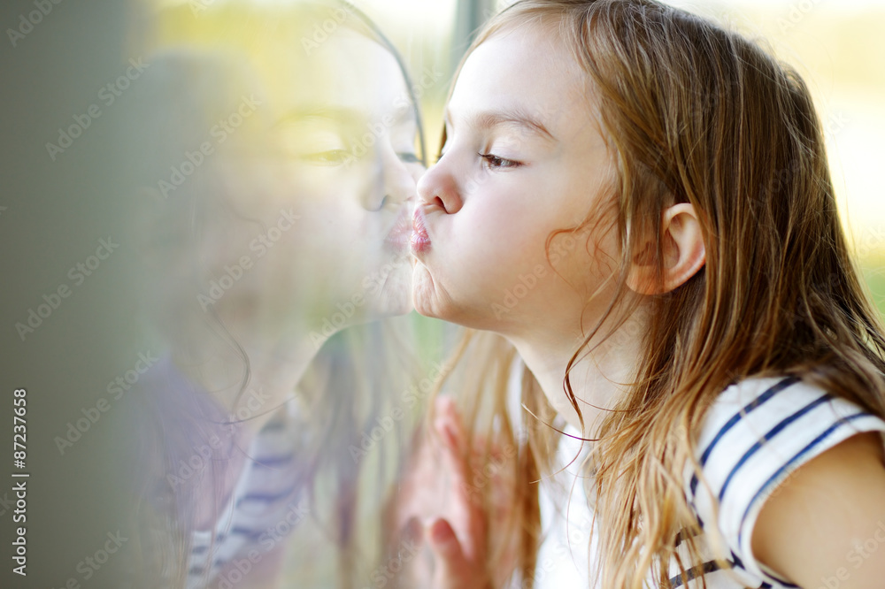 Funny girl kissing her reflection on a window 스톡 사진 Adobe Stock
