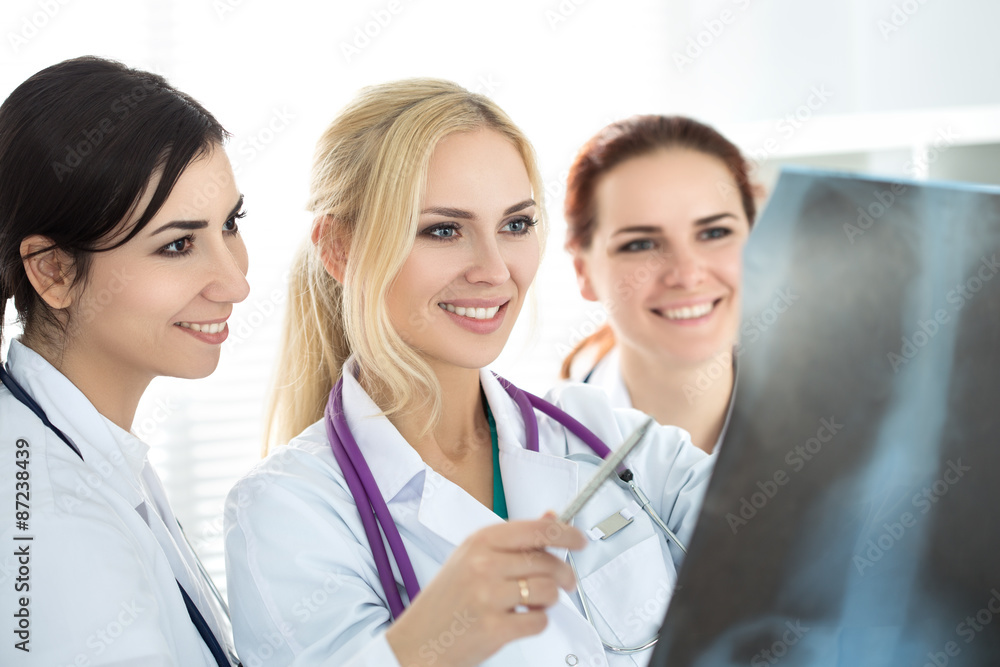 Three smiling female medicine doctor looking at x-ray picture. Healthcare and medicine concept. Three smiling female medicine doctor looking at x-ray picture. Healthcare and medicine concept.