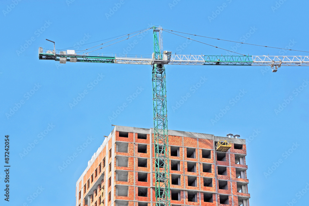 Crane and building construction site against blue sky Crane and building construction site against blue sky