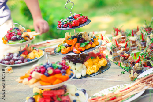 Beautifully decorated catering banquet table with different food snacks and appetizers with sandwich, caviar, fresh fruits on corporate birthday party event or wedding celebration  © tsuguliev
