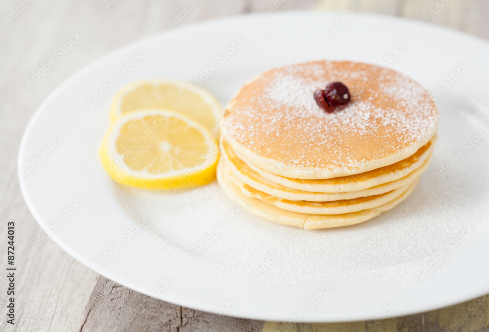 Stack of homemade pancakes with lemon on wood table Stack of homemade pancakes with lemon on wood table