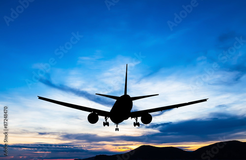 Silhouetted commercial airplane flying at sunset