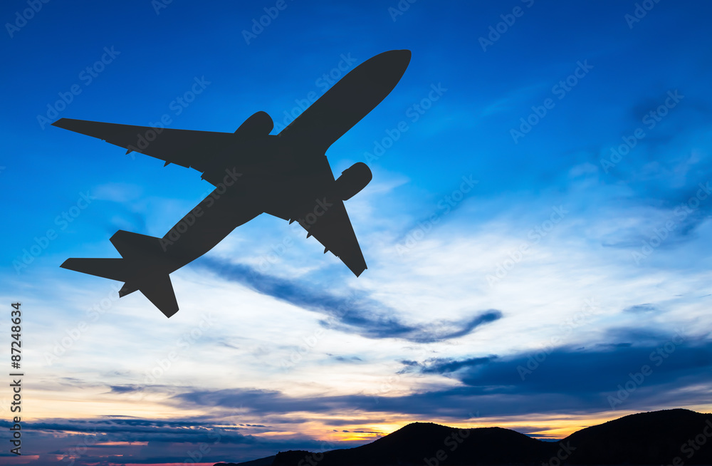 Silhouetted commercial airplane flying at sunset Silhouetted commercial airplane flying at sunset