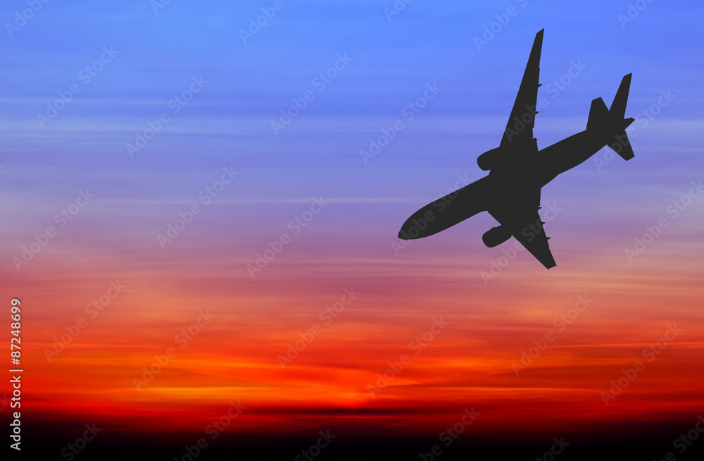 Silhouetted commercial airplane flying at sunset