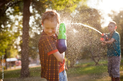 happy little boys playing with water guns