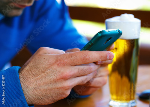 Closeup of male hands with  smart phone and  beer background photo