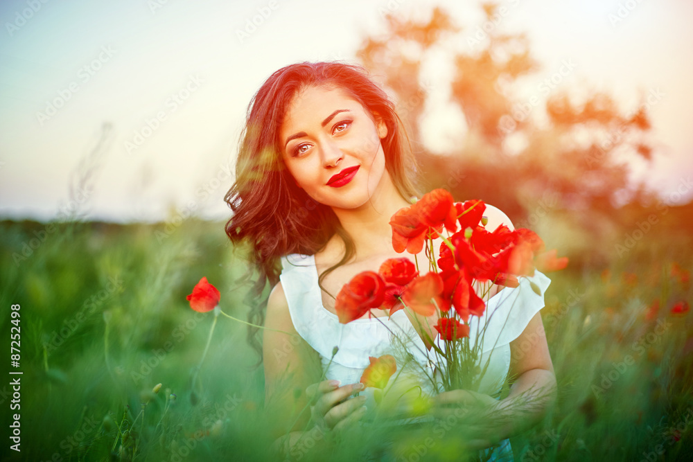 Naklejka premium Beautiful woman in a poppy field with flowers