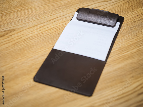 Blank Bill Receipt Restaurant Clip in pad on Table photo