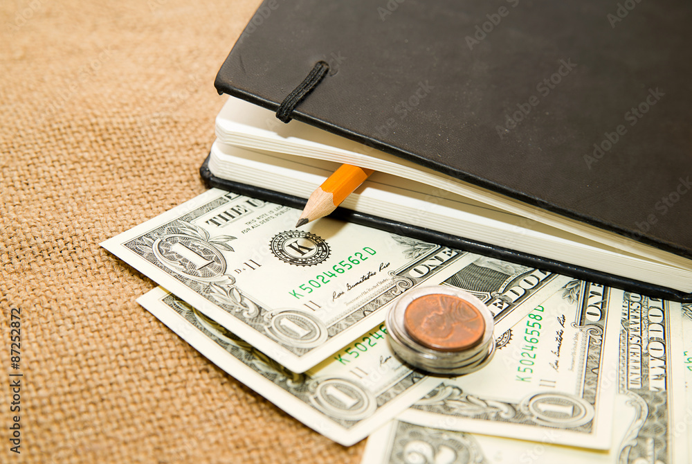 Naklejka premium notebook, pencil and money on the old tissue