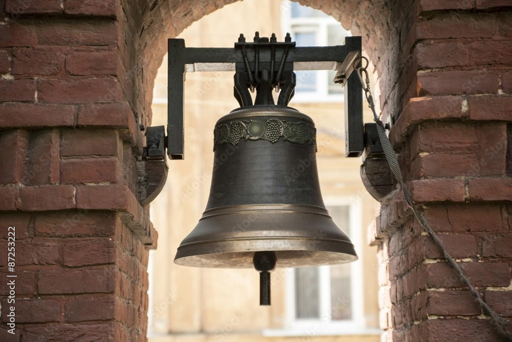 Fototapeta premium The old bronze bell near the brick wall