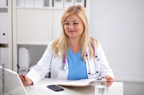 Portrait of young woman doctor in white coat at computer