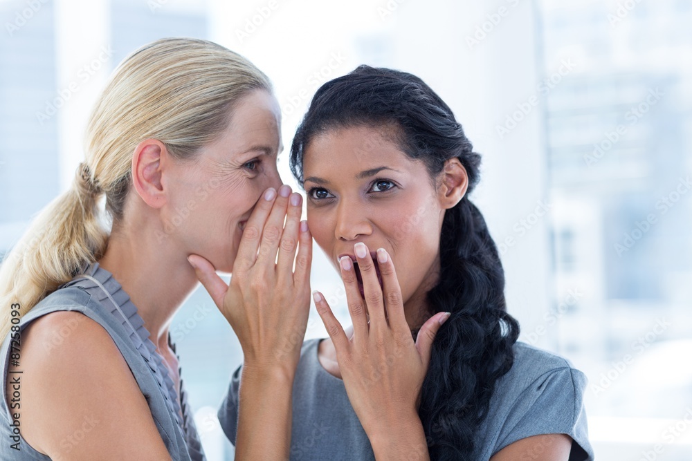 Businesswoman whispering gossip to her colleague Businesswoman whispering gossip to her colleague