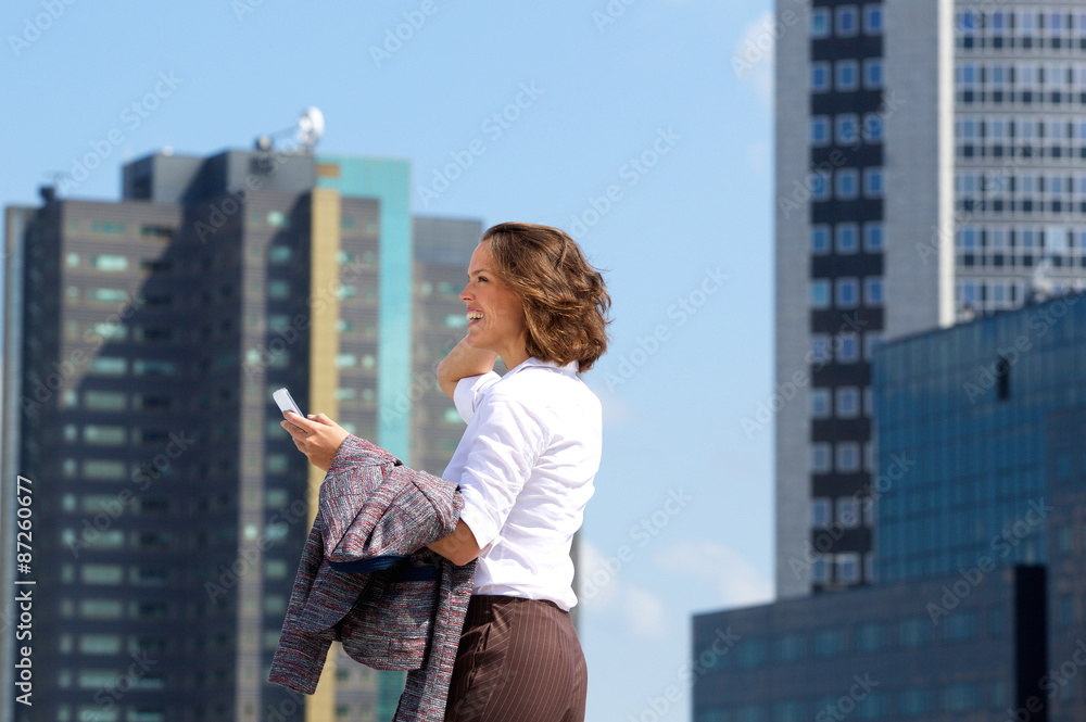 Business woman walking in the city with mobile phone