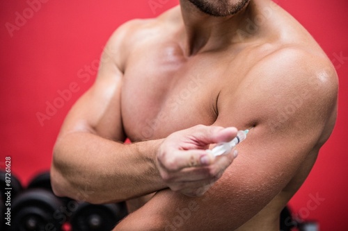 Muscular man injecting steroids photo