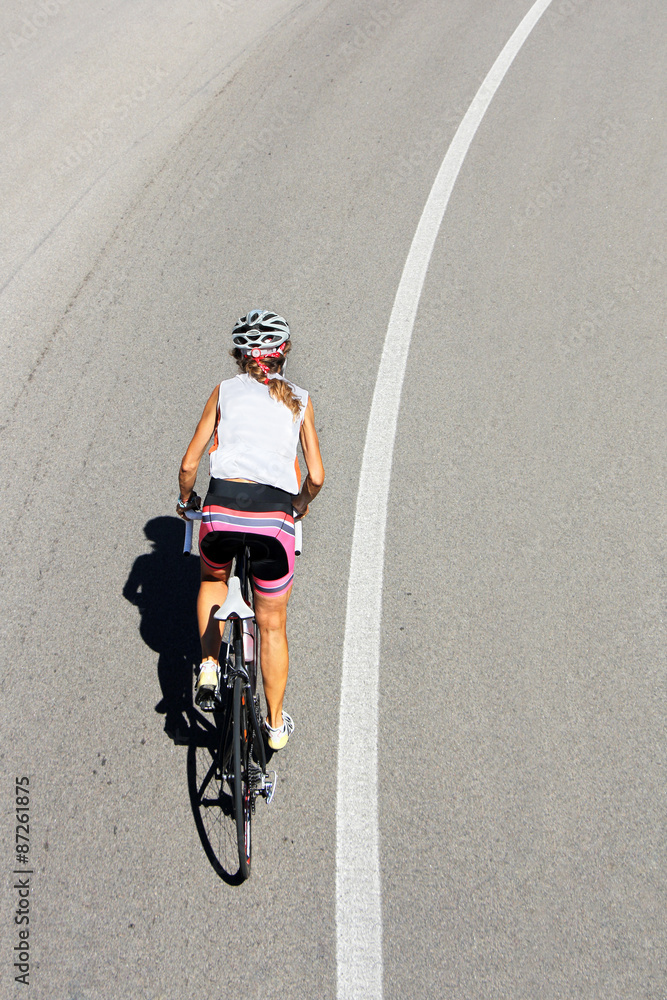Cyclist woman riding a bike on an open road