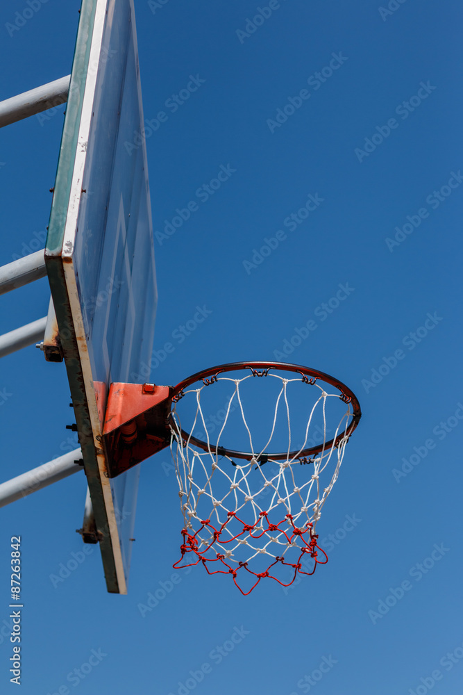 Basketball board and hoop with blue sky.