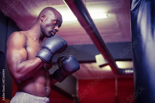 Young Bodybuilder standing in front of a boxingbag