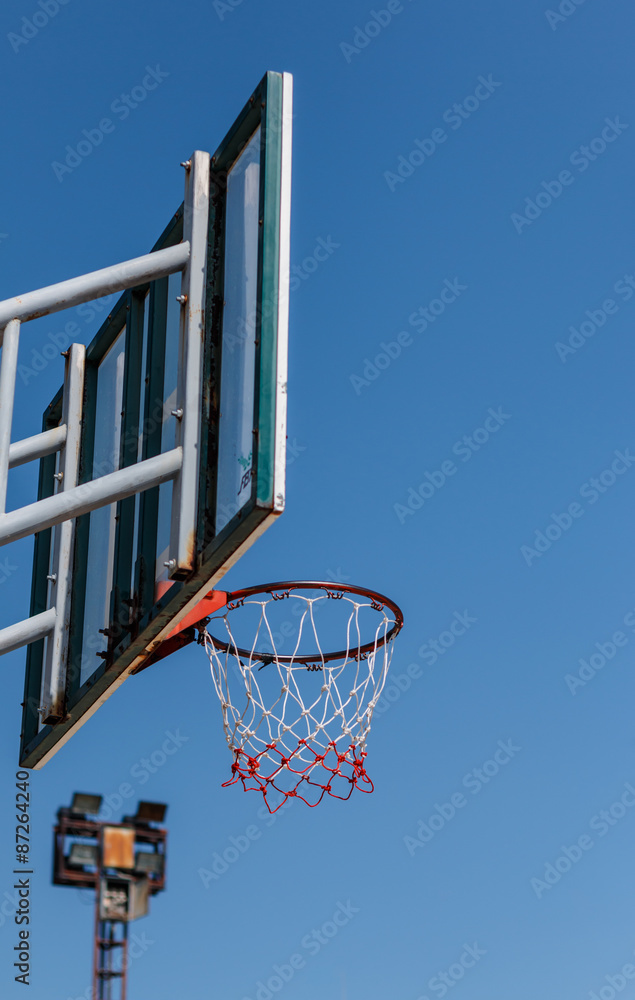 Basketball board and hoop with blue sky background.