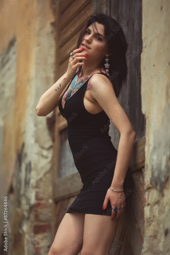 Obraz premium beautiful girl in a black dress stands near architectural struct