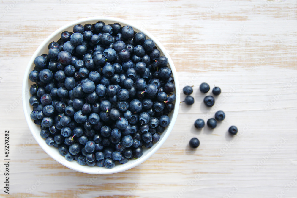 Fresh bilberry in a white ceramic bowl on a wooden surface Fresh bilberry in a white ceramic bowl on a wooden surface