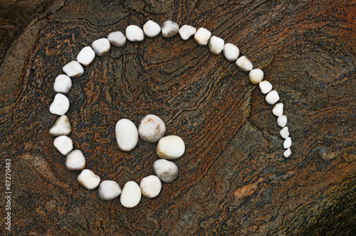 Esoterische Spirale aus weißen Kieselsteinen auf geädertem Felsen