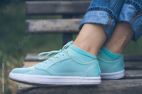 Female feet in jeans and sports shoes