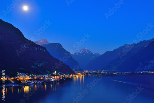 City at night. Moon over silhouettes of mountains. Switzerland