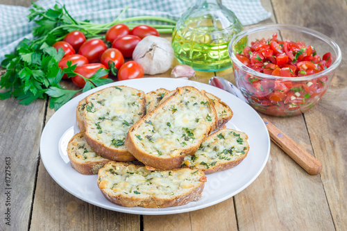 Making tomato bruschetta: garlic cheese crostini and chopped tomatoes with herbs