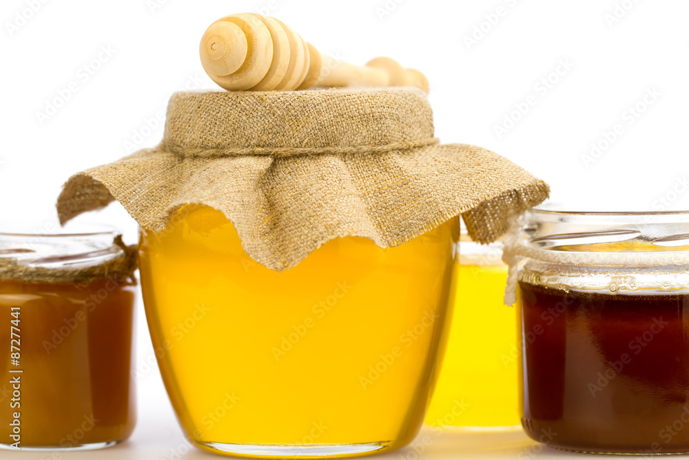 glass jar of fresh honey with drizzler and flowers isolated on white background glass jar of fresh honey with drizzler and flowers isolated on white background